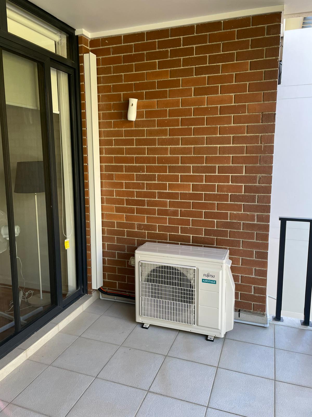 Fujitsu split system outdoor unit installed on apartment balcony with tidy pipework