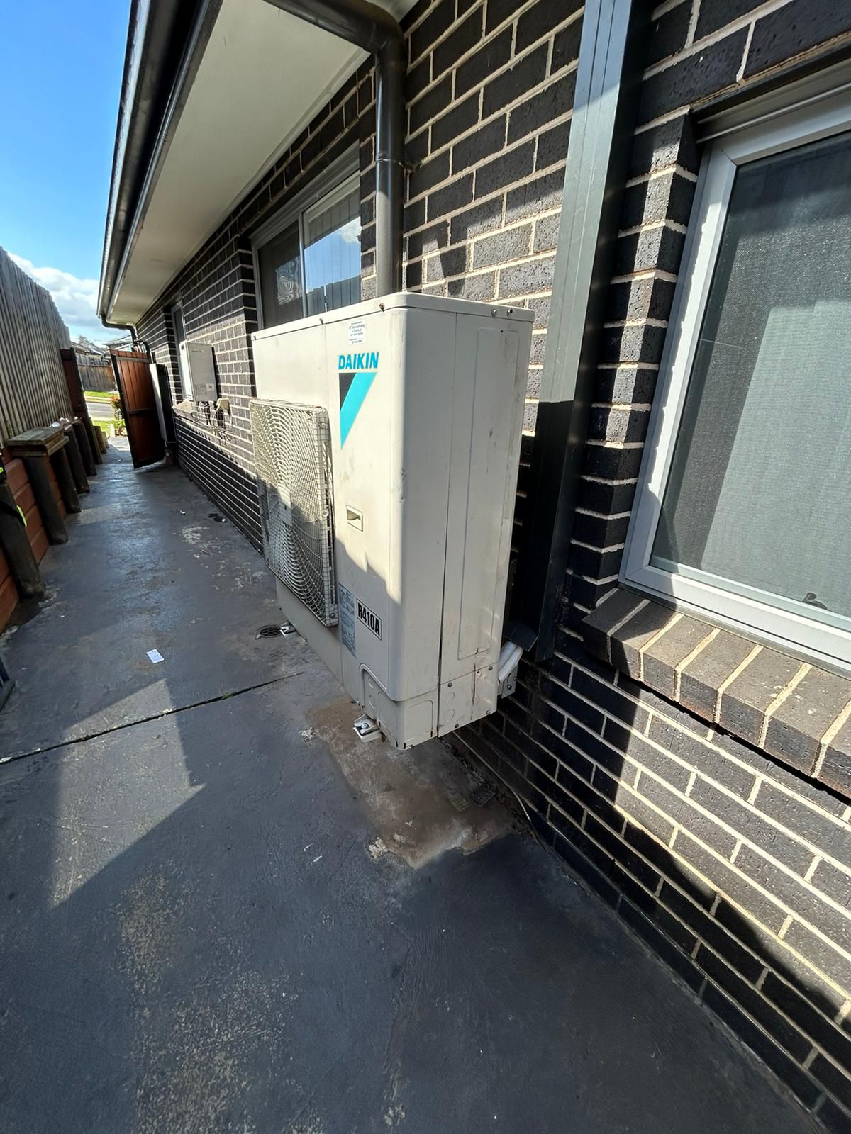 Daikin ducted outdoor unit installed on side passage of brick home